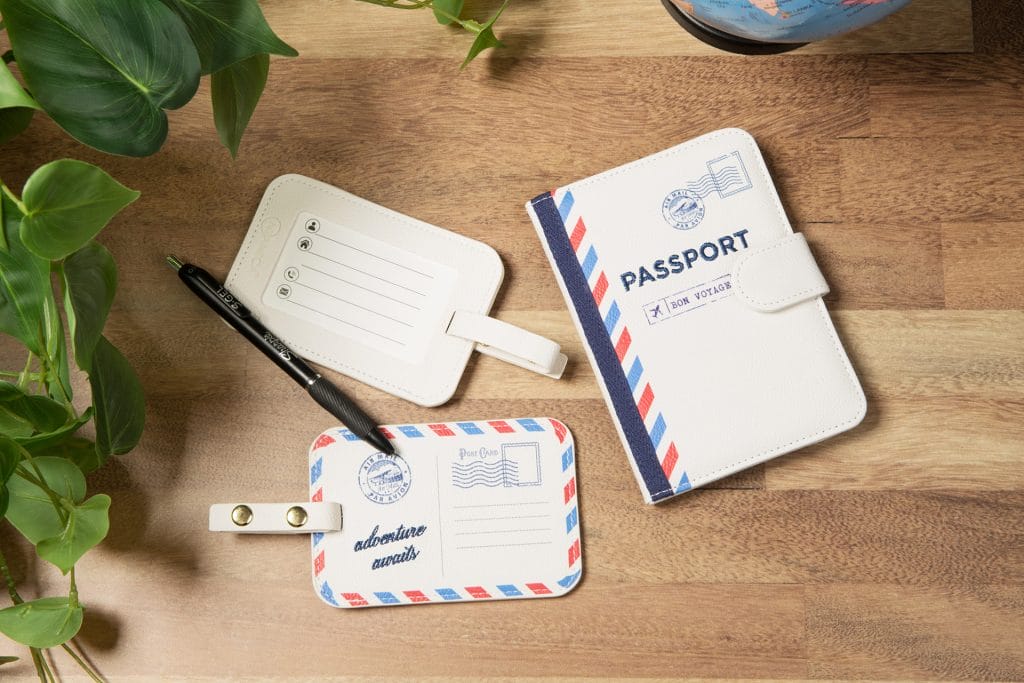 Image of Miamica's See the World travel accessories: ivory luggage tags and an ivory passport case. They feature a fun red, white & blue vintage post card design.